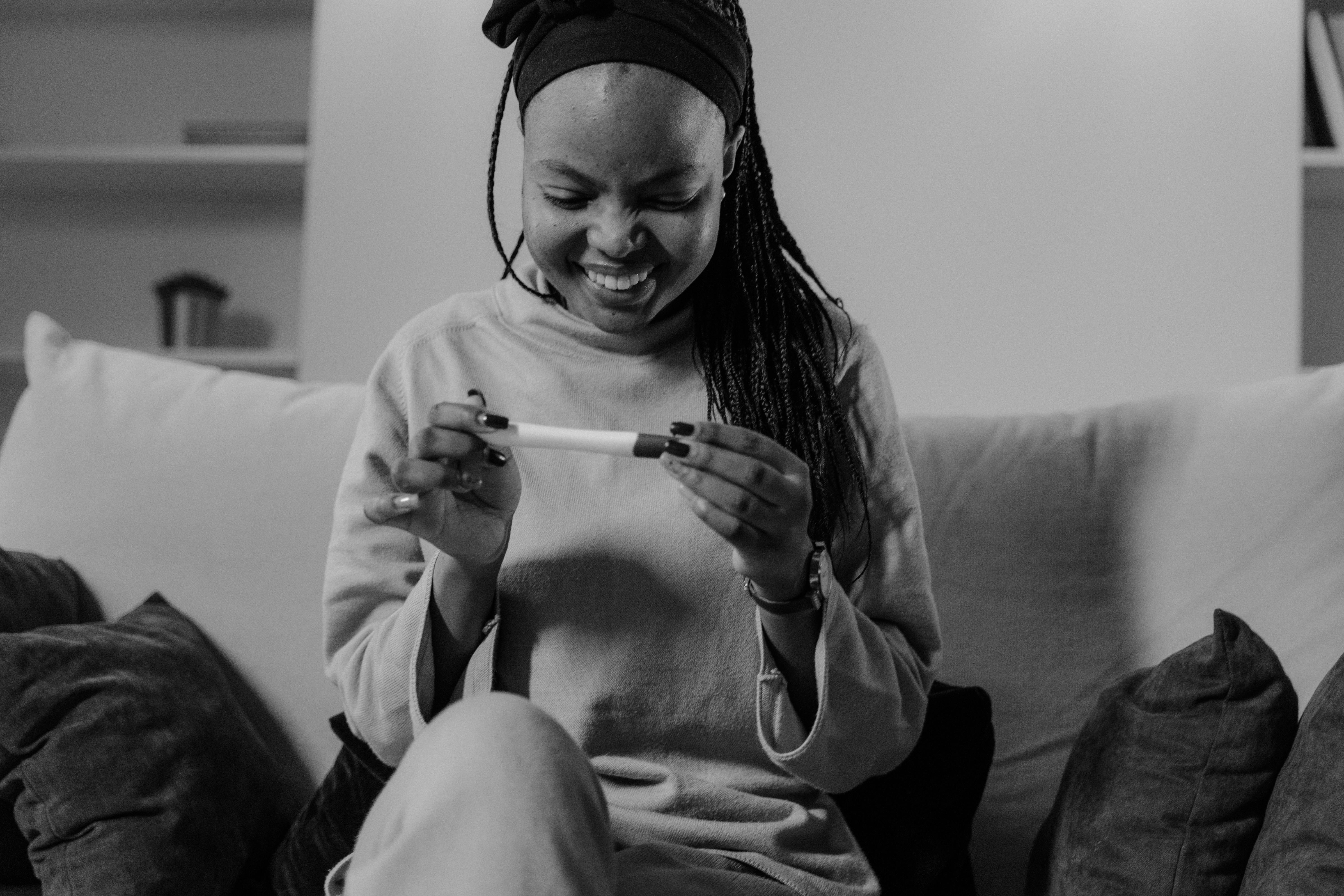 woman holding a pregnancy test while sitting on couch