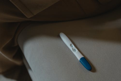 White and Blue Pregnancy Test on Gray Textile