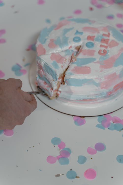 Free Close-up of a gender reveal cake with a slice taken out surrounded by confetti. Stock Photo