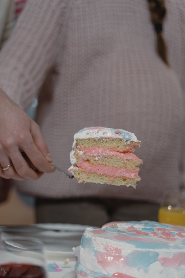 A Person Holding A Slice Of Cake