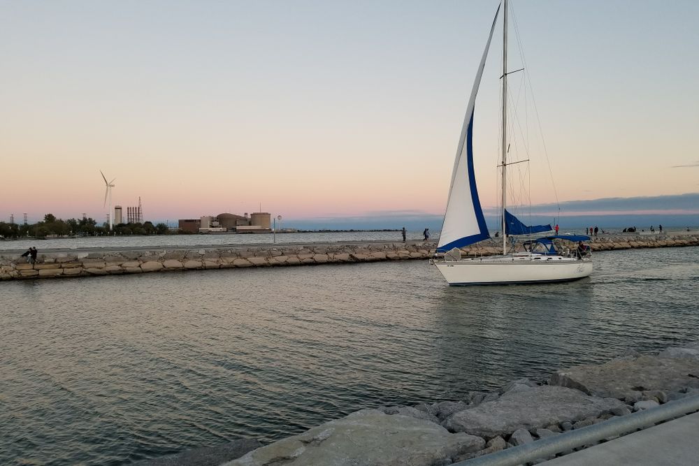 Sailboat cruising on tranquil waters at sunset in Pickering, Ontario, Canada.