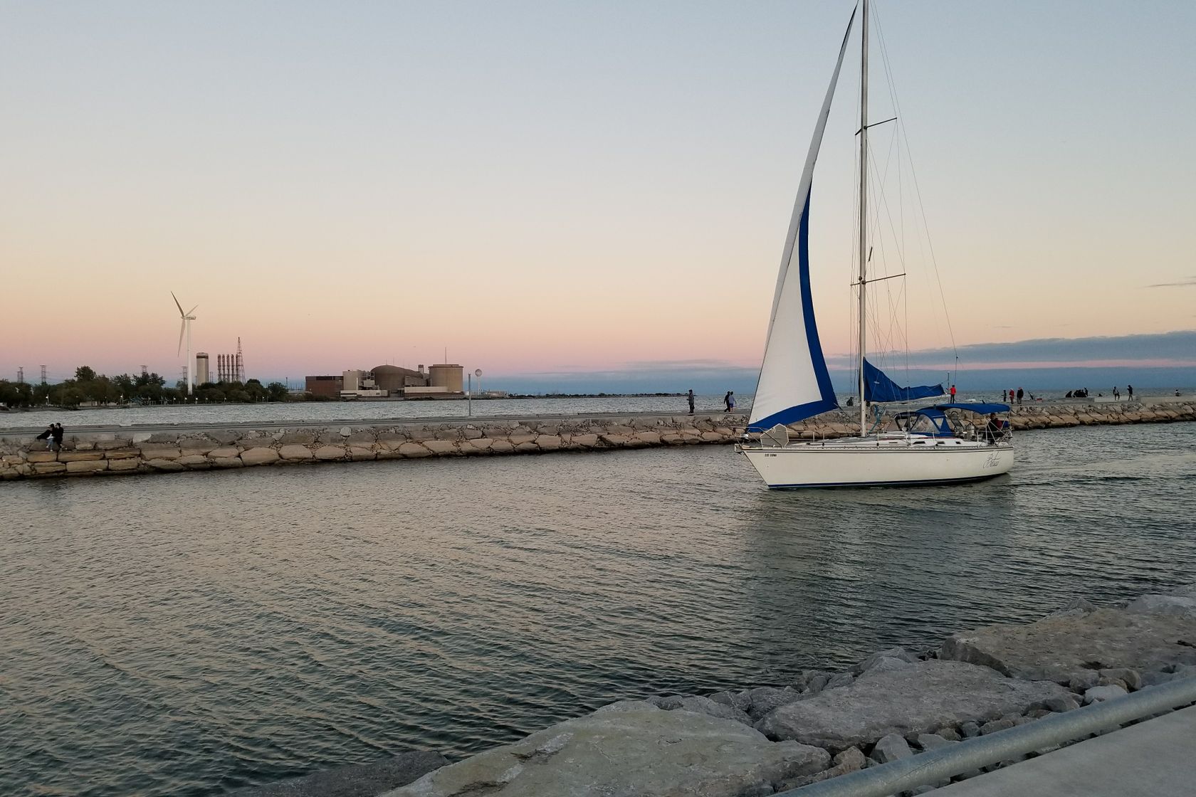 Sailboat cruising on tranquil waters at sunset in Pickering, Ontario, Canada.