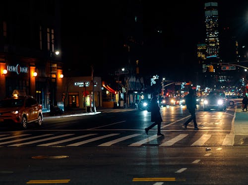 Pedestrian crossing busy road in modern city in autumn evening