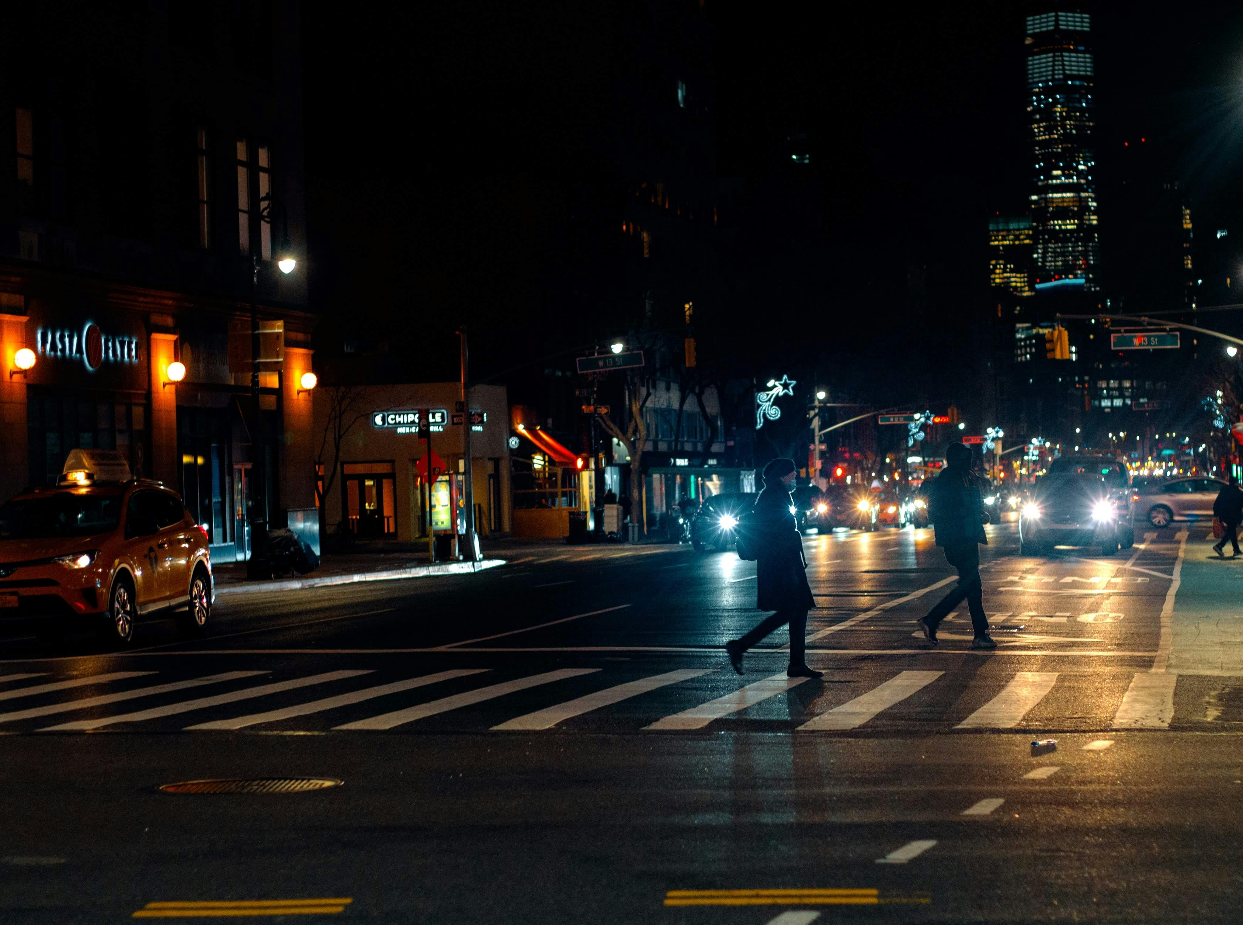 Night shot of pedestrians crossing road full of mopeds in busy