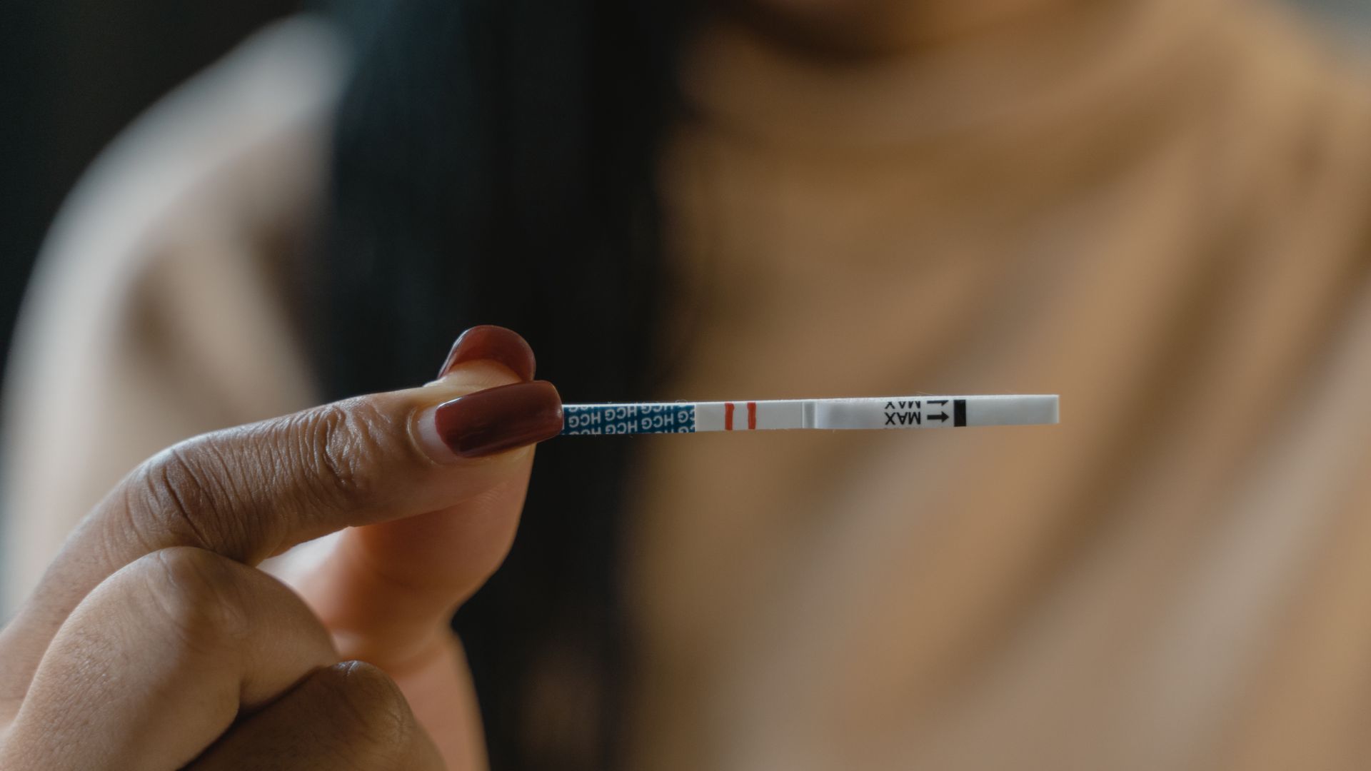 Modafinil Effect on Fertility: What You Need to Know A hand holds a positive pregnancy test strip against a blurred background, symbolizing new beginnings — modafinil effect on fertility