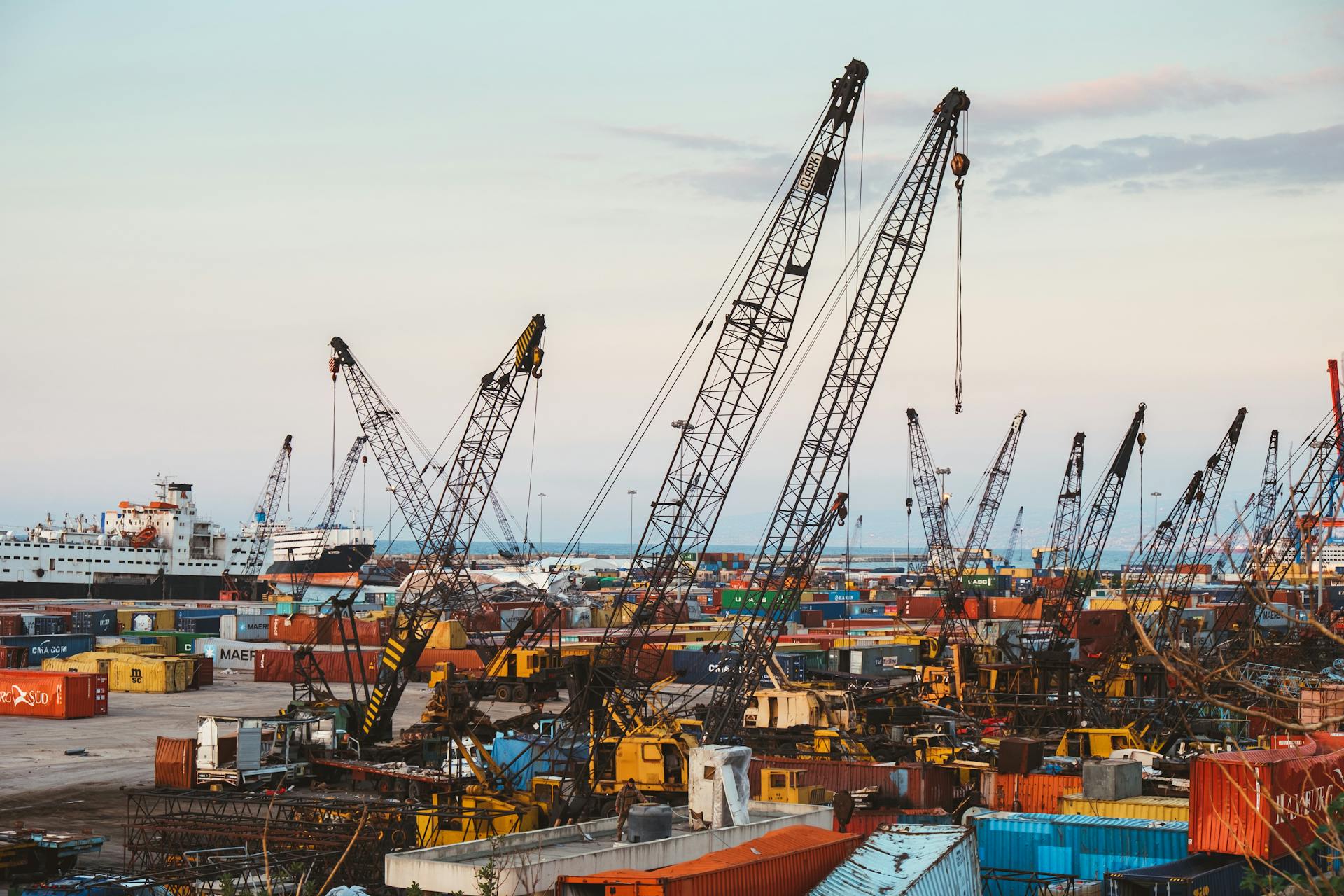 A bustling industrial port in Beirut with cranes and cargo containers.