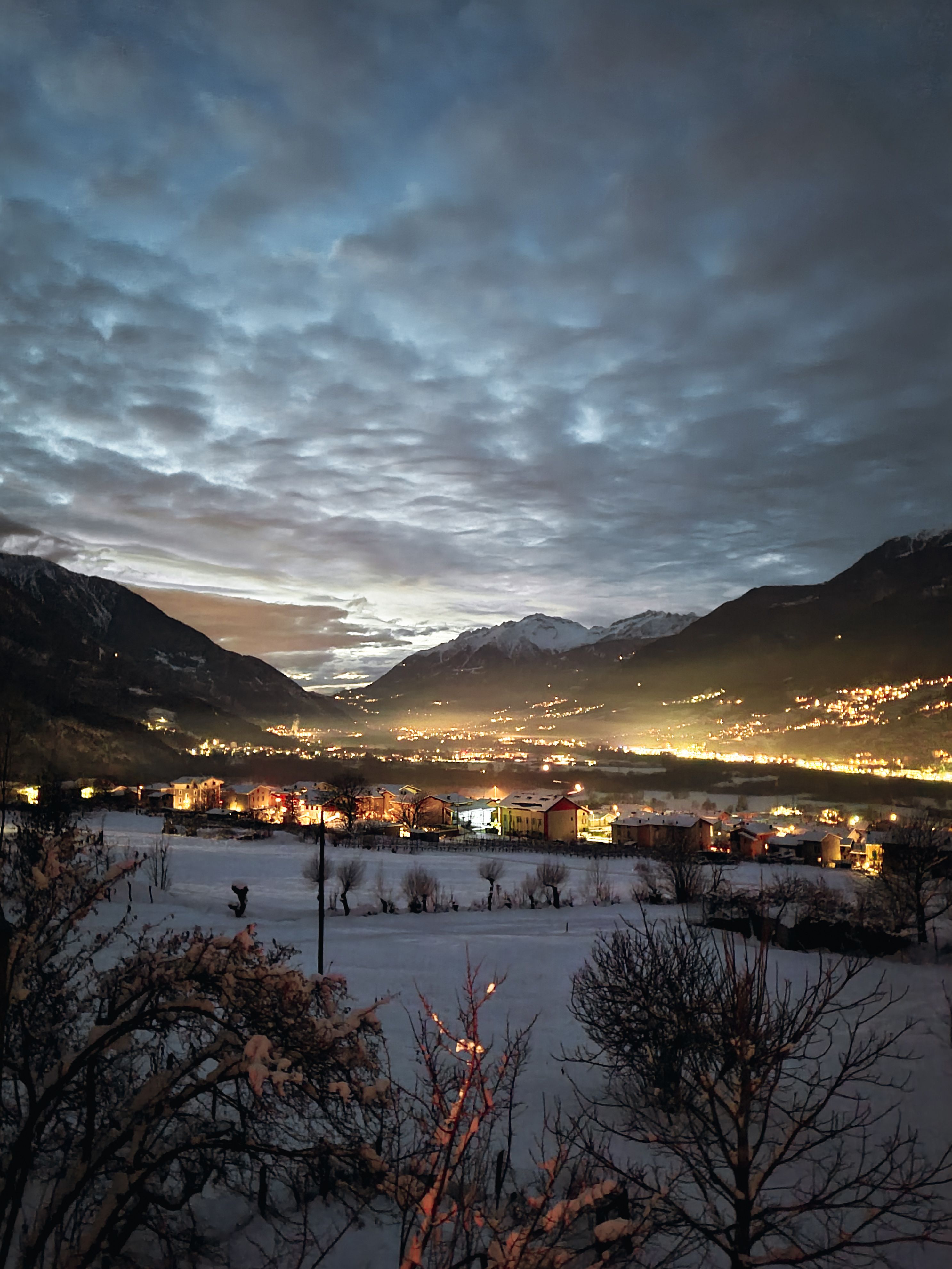 Captivating winter evening view of a snow-covered village nestled among mountains.