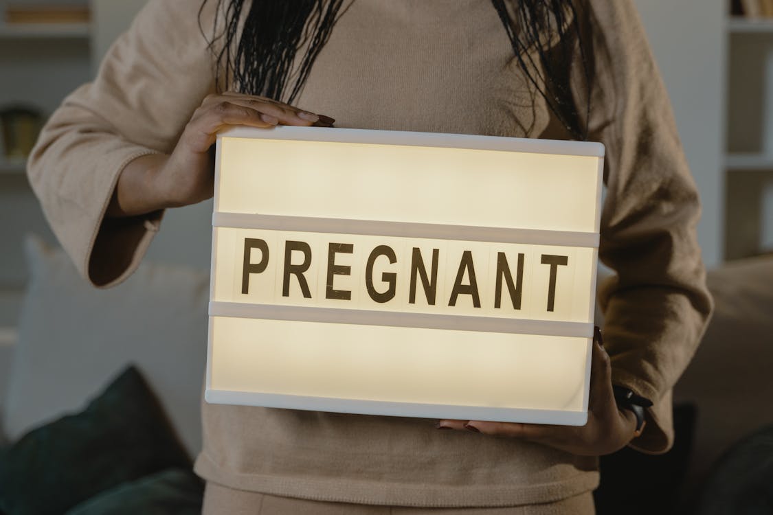 Free Woman Holding A Box With Pregnant Text Stock Photo