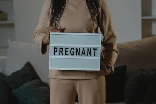 Free A Woman Holding a Sign That Says Pregnant Stock Photo