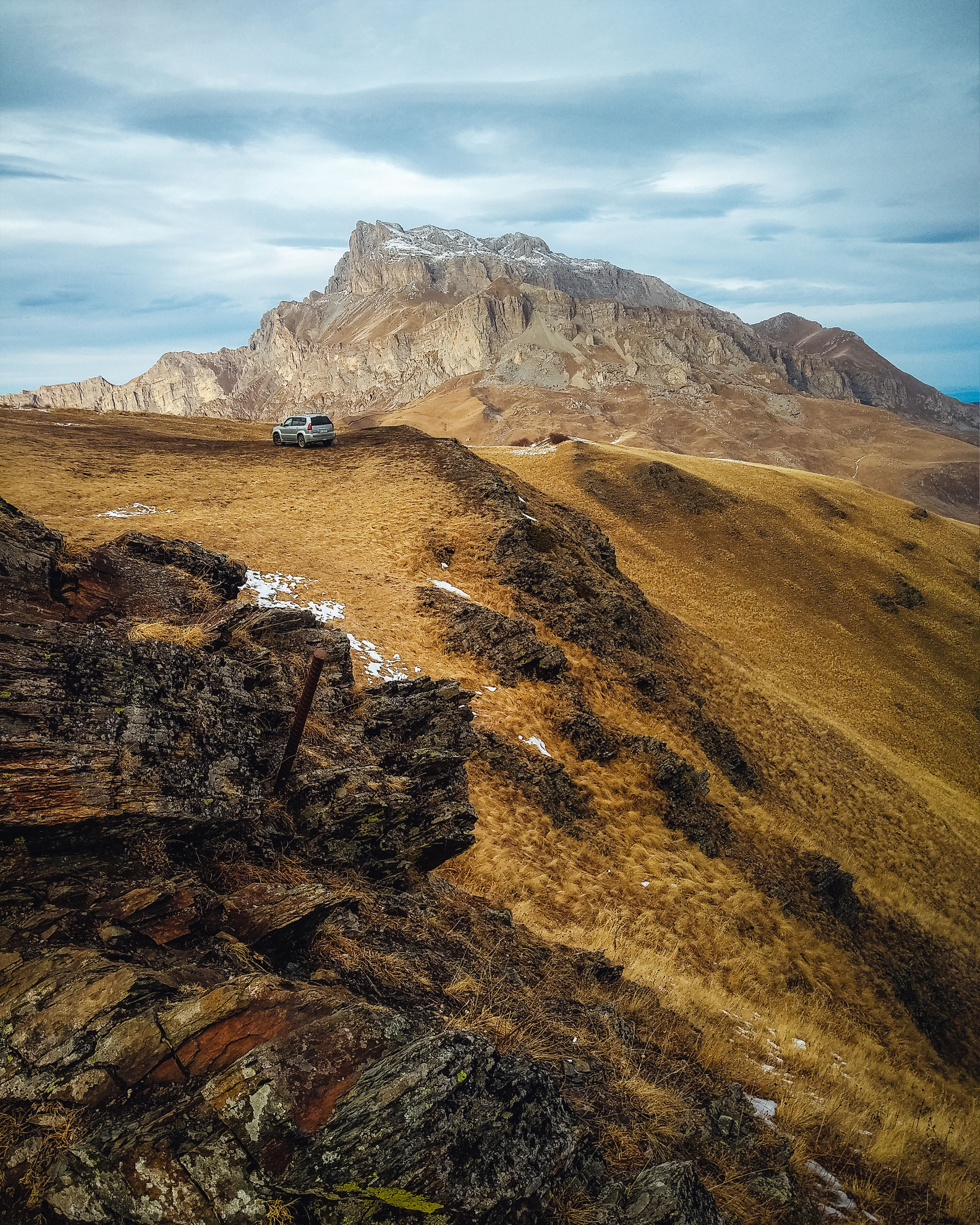 Breathtaking view of rugged mountains and a lone car in North Ossetia-Alania, Russia.