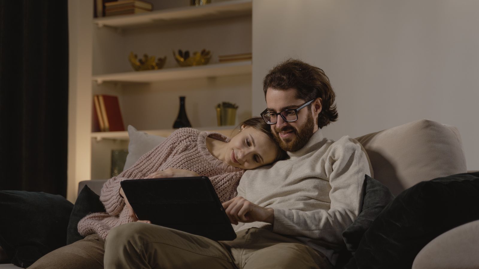 Two adults reading a tablet together on a sofa