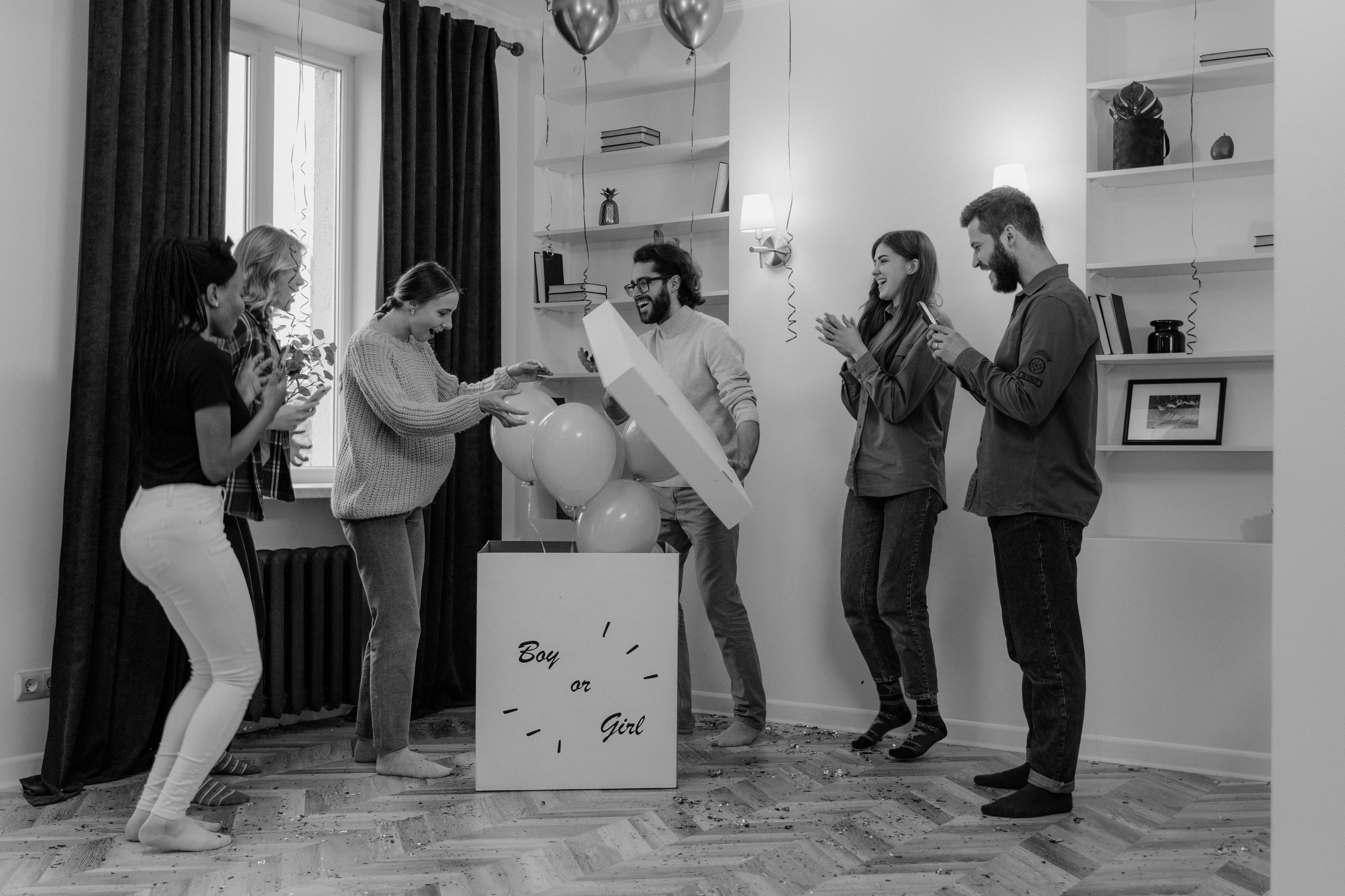 People opening balloon gift box on gender reveal party at home