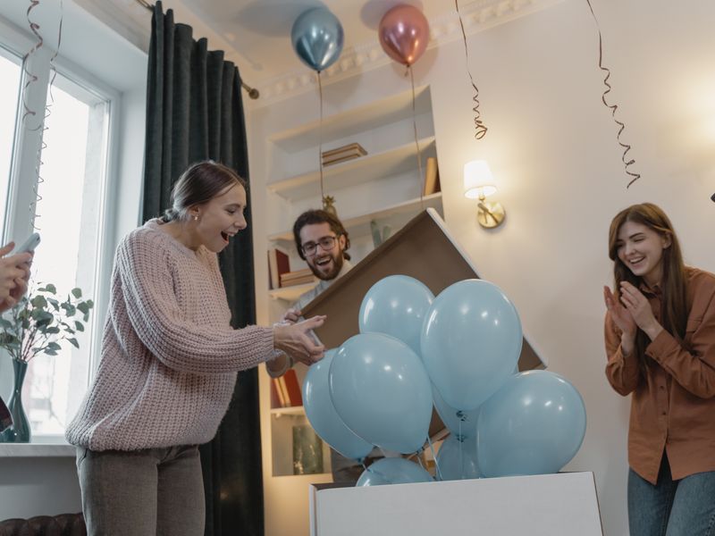 Mother-to-be delighted by blue balloons at a gender reveal