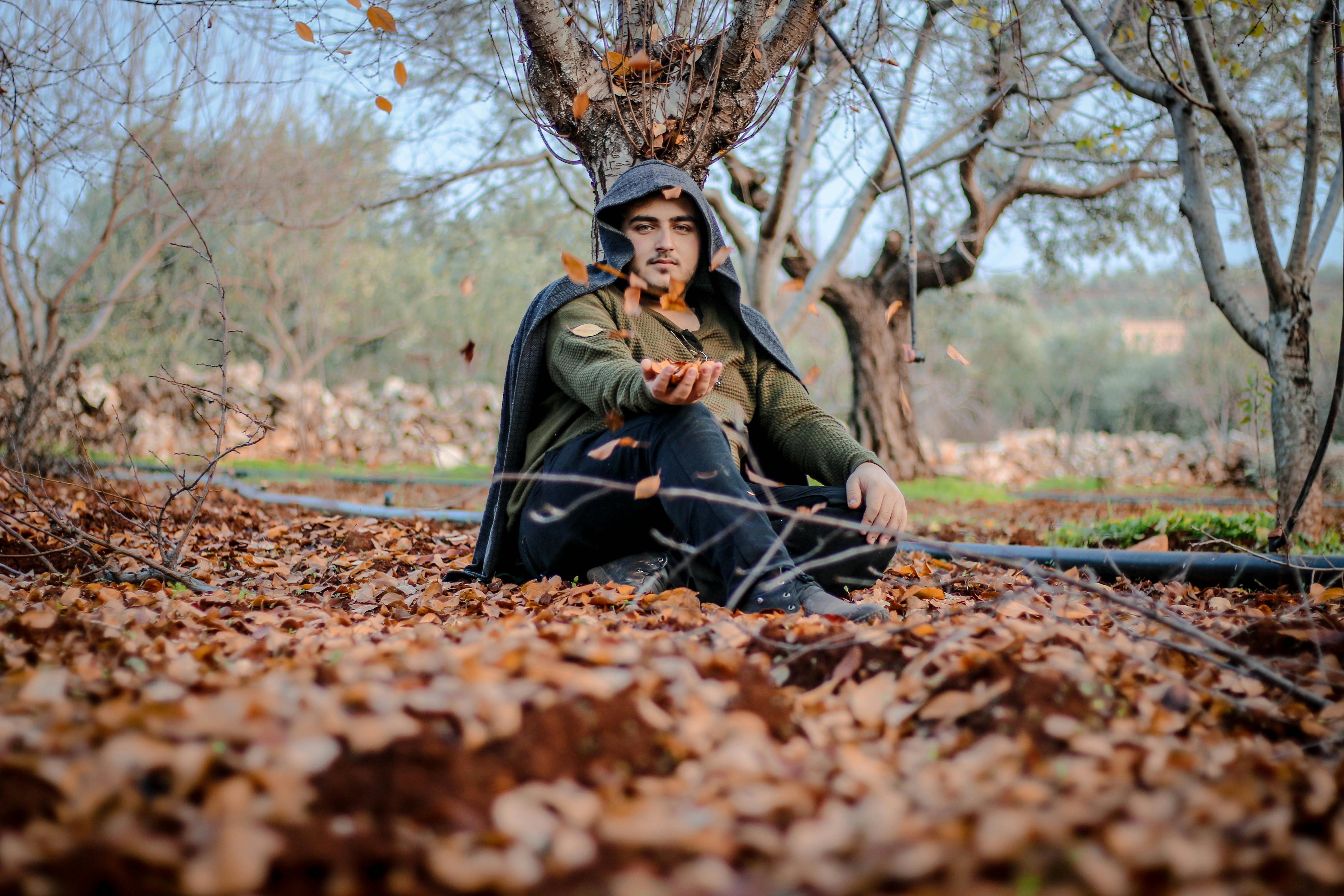 man sitting under bare trees in autumn park