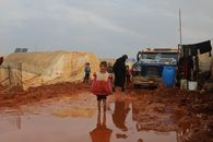 Joyful ethnic girl standing in dirty puddle