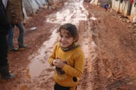 Smiling ethnic girl standing on dirty ground
