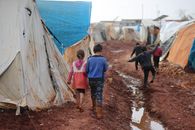 Children walking on dirty street with tents