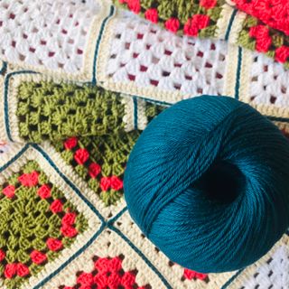 Granny-square crochet blanket with a teal yarn ball, photo by Mara Cotta on Pexels