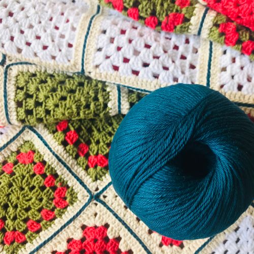 Free Close-up of a colorful crochet blanket with a teal yarn roll, highlighting fiber art. Stock Photo