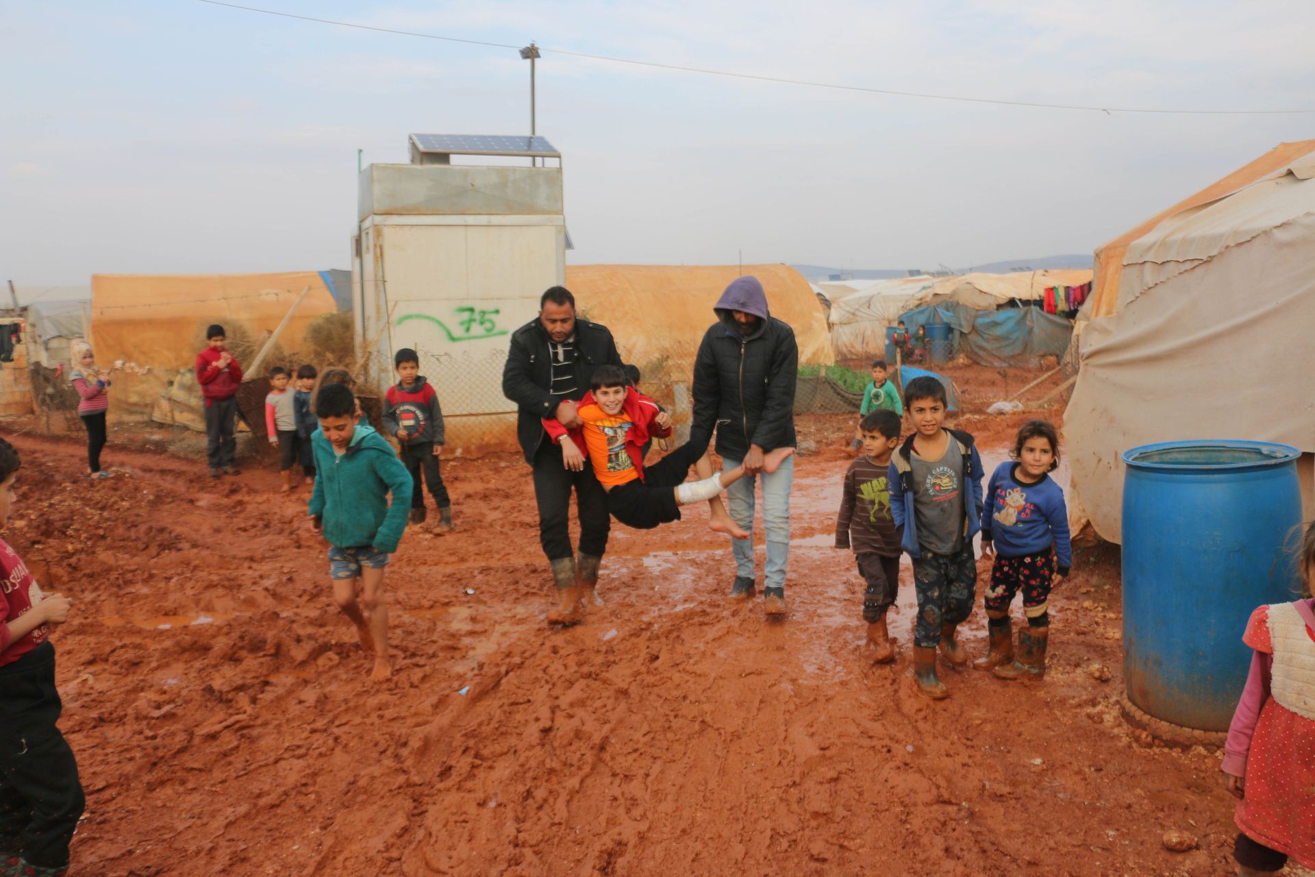 Children enjoy playful moments in a muddy Syrian refugee camp in Idlib.