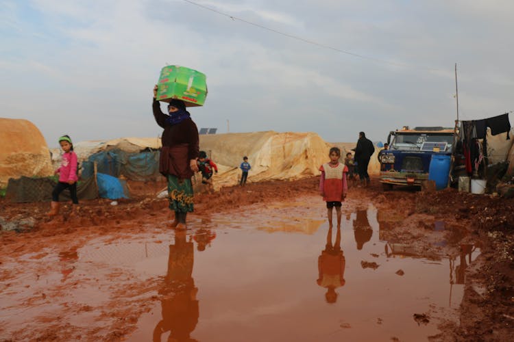 Ethnic Children And Adults Refugees Walking On Dirty Ground