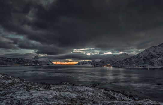 Breathtaking view of snow-capped mountains under thick clouds, showcasing winter's serene beauty.