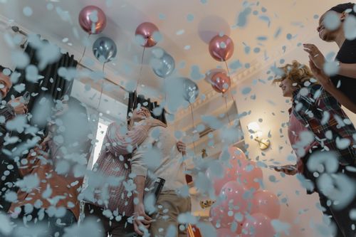 Free Happy group celebrating indoors with balloons and confetti. Joyful and festive atmosphere. Stock Photo