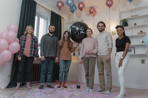 Free A group celebrates a gender reveal party indoors with balloons and decorations. Stock Photo
