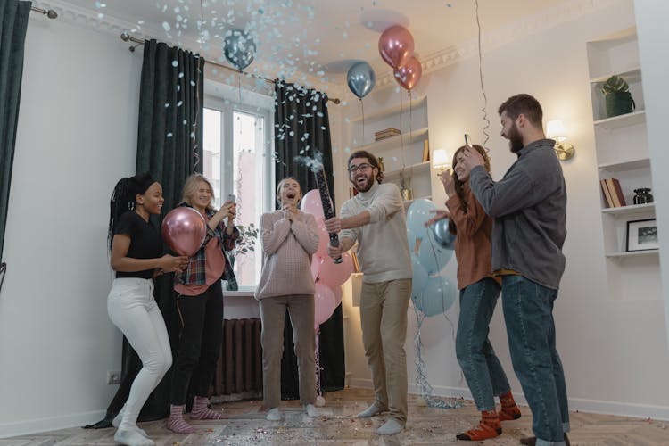 Happy People Looking At The Blue Confetti  In The Air