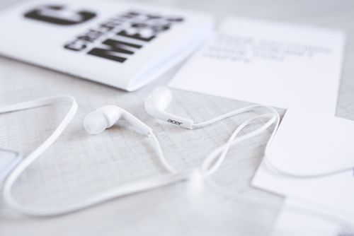 Free Close-up of white earphones with a modern minimalist aesthetic on a desk. Stock Photo