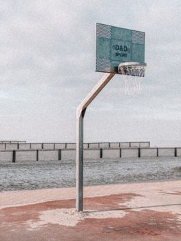 Lonely basketball hoop with a vintage feel by a bustling seaside, capturing serenity.