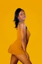 Photo of a Beautiful Woman in a Mustard Dress Looking at the Camera
