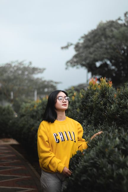 Woman enjoying a serene outdoor moment in casual wear with lush greenery.