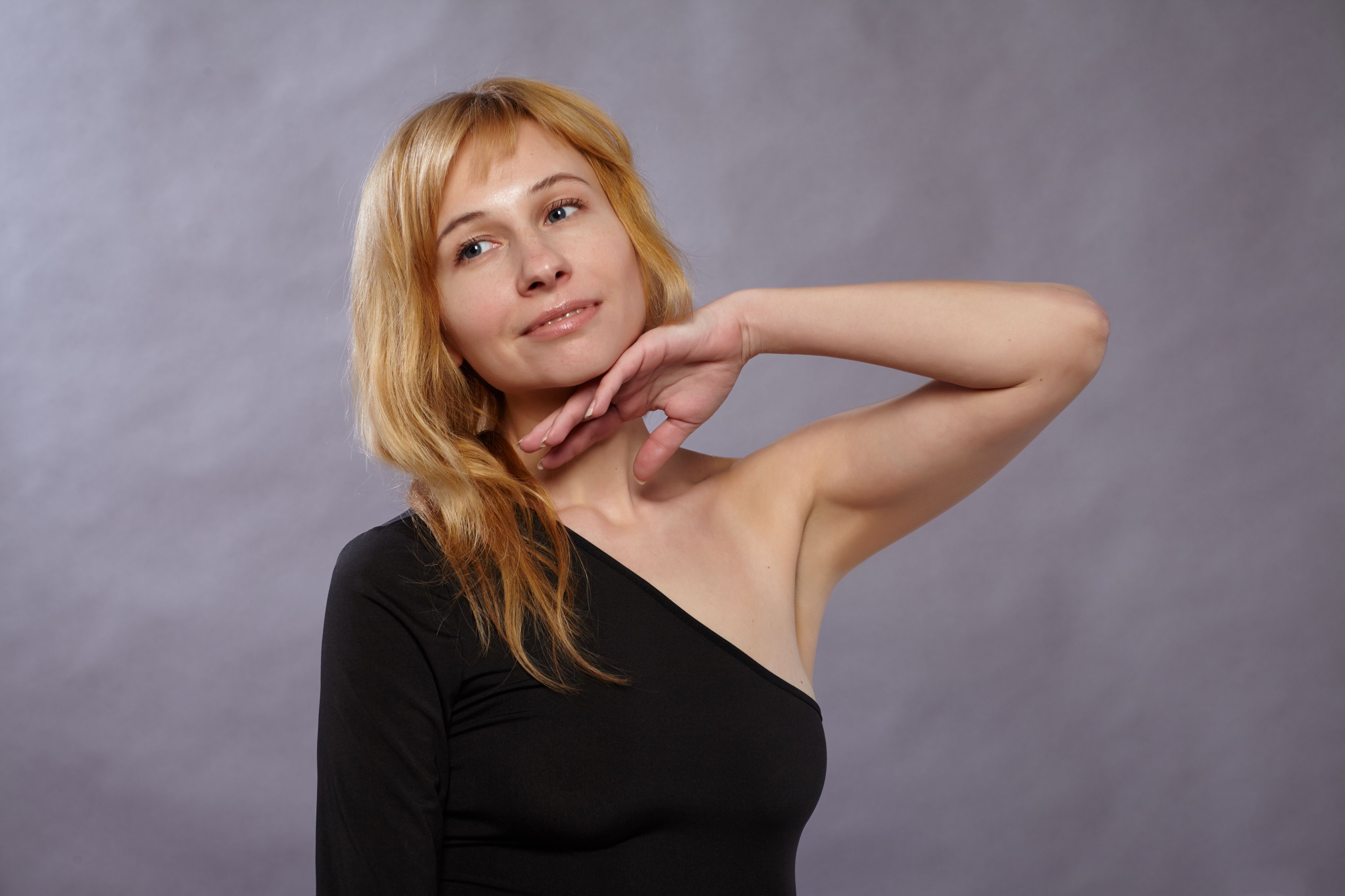 Charming adult woman posing elegantly in a studio setting, capturing a graceful and serene expression.