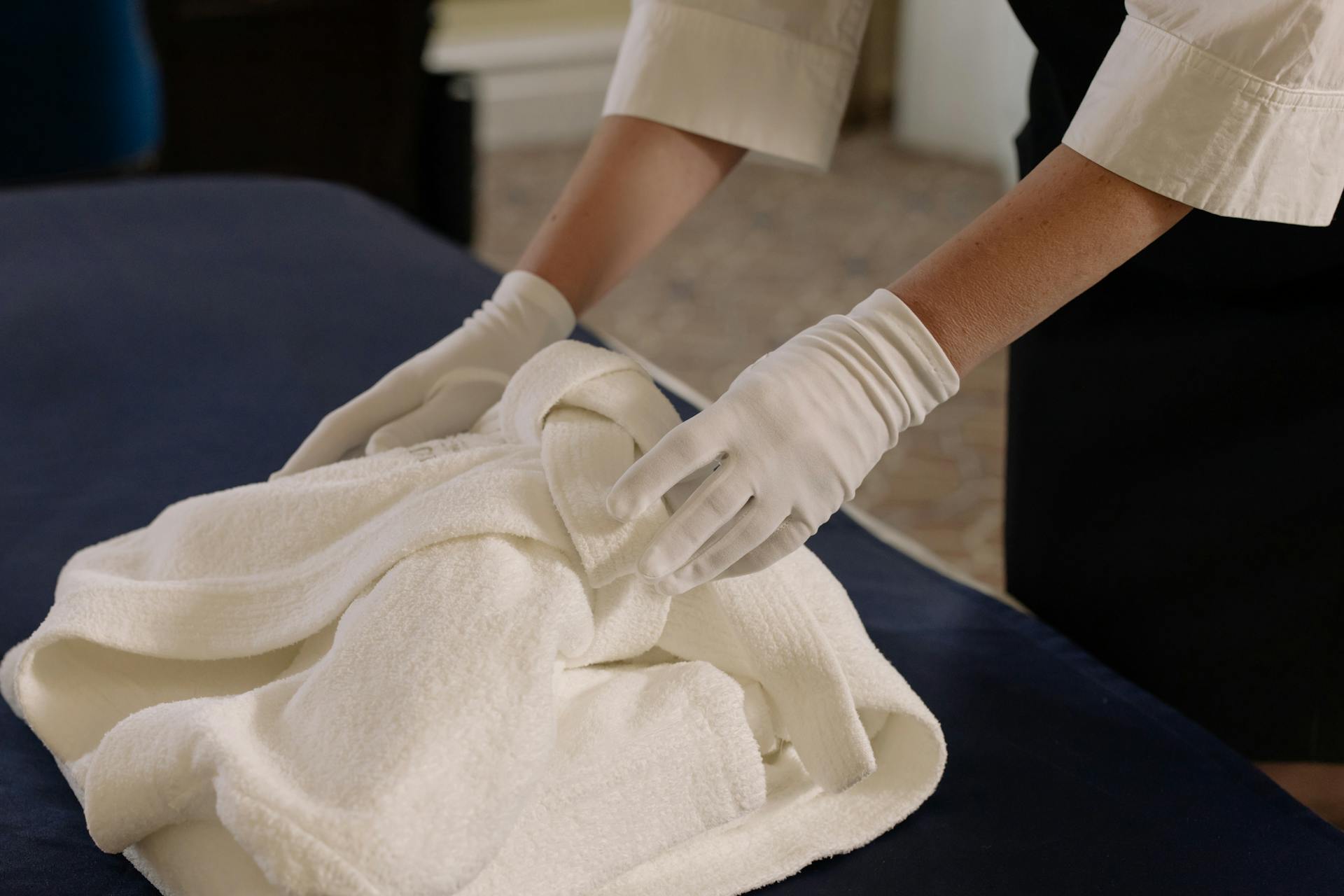 A housekeeper tidily arranging bath linens in a hotel room, showcasing cleanliness and attention to detail.