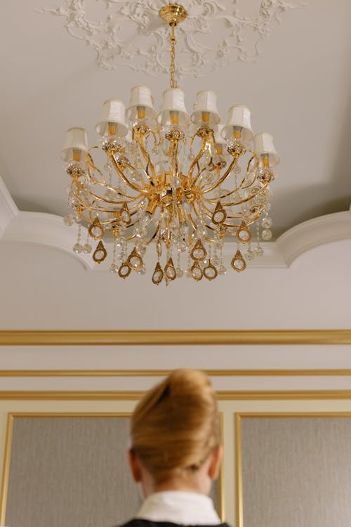 Free Woman Standing Under a Chandelier of a Hotel Room Stock Photo