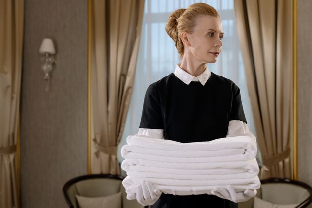 Elegant hotel housekeeper holding fresh, neatly folded white towels in a luxurious room. Related image for Cybersecurity Lessons for Modern Hospitality Teams.