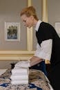 A Chambermaid Stacking Towels on Bed