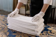 Person Holding a Stack of White Towels