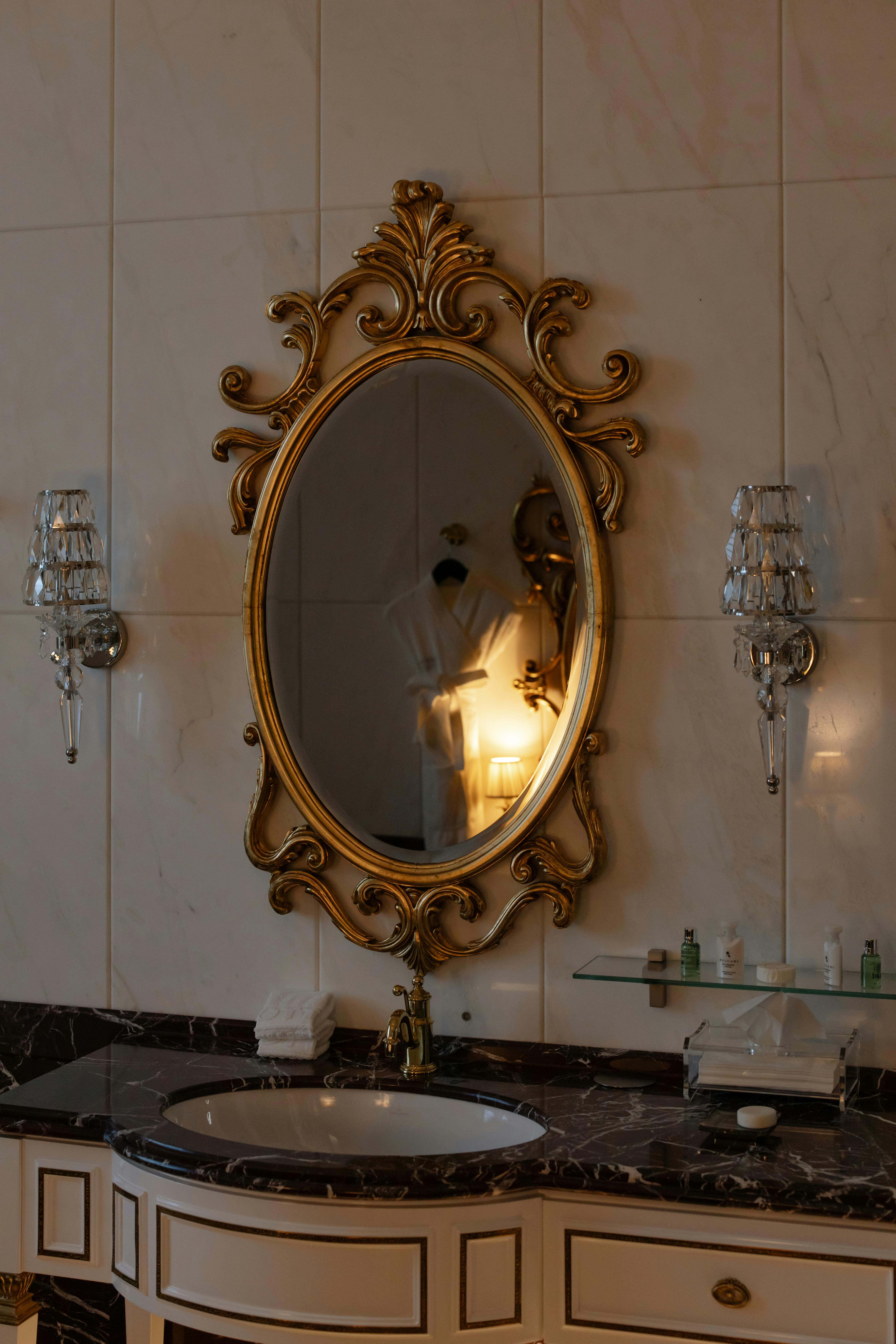 bathroom sink with classic mirror on wall beside two lamps