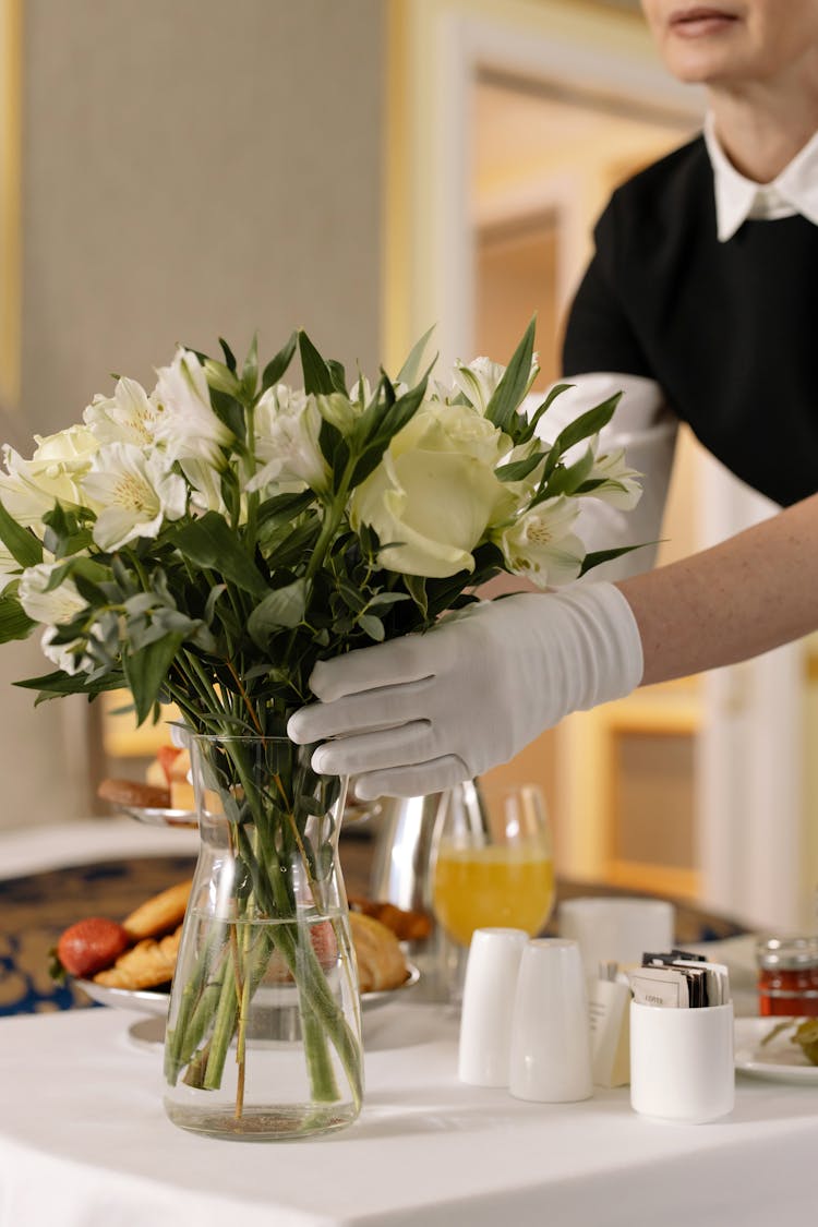 Woman Arranging Flowers In A Glass Vase