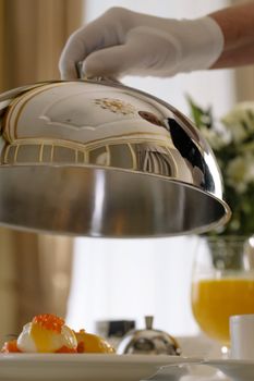 Elegant breakfast presentation featuring poached eggs with caviar and orange juice.