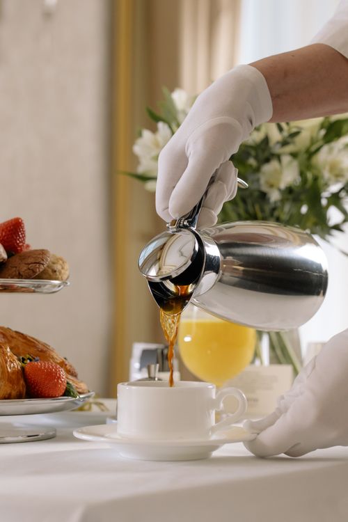 Free Elegant morning setup with coffee and pastries served by a gloved hand, showcasing luxury room service. Stock Photo