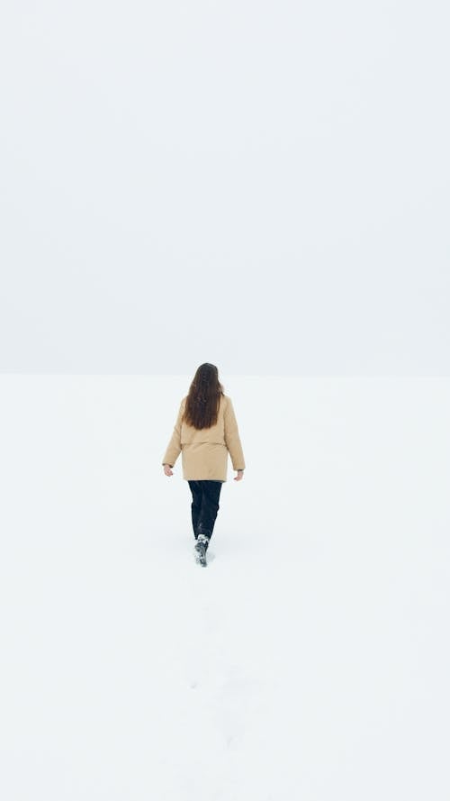Woman in Beige Jacket Walking on White Snow Covered Ground