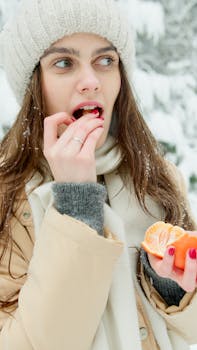A woman savoring an orange amidst a snowy landscape, highlighting the contrast of bright fruit against winter scenery.