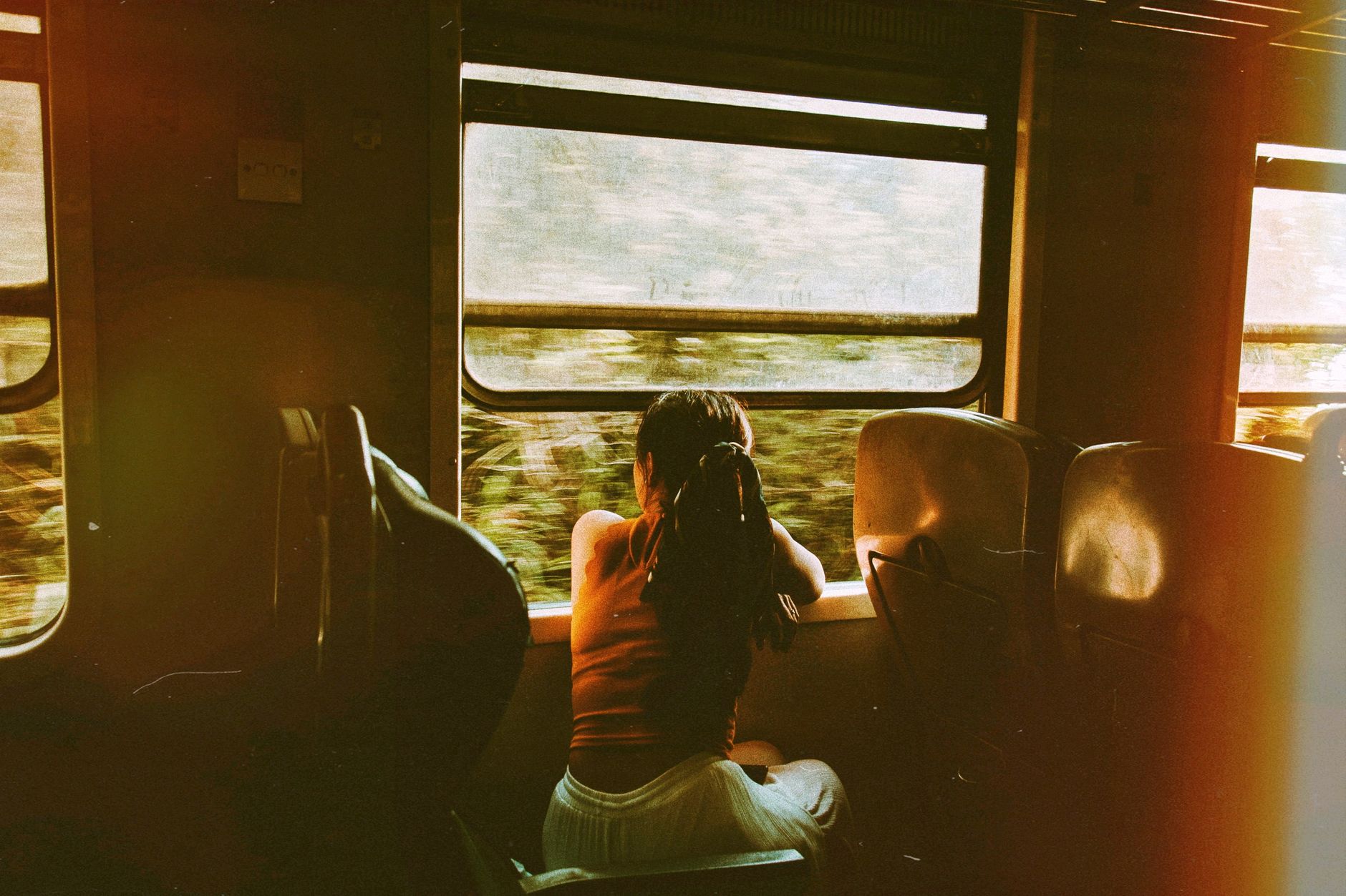 Best Train Between Madrid and Barcelona 9 A woman gazes out of a train window, enjoying a serene journey through lush scenery.