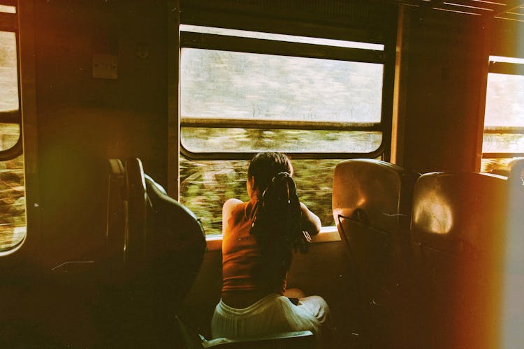 Unrecognizable Woman Riding Train And Looking Out Window