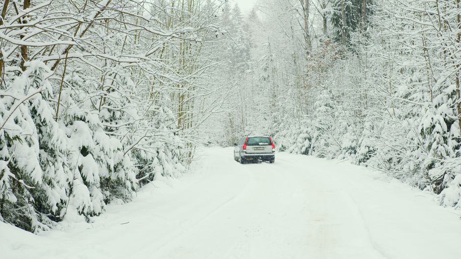 Car equipped with winter tires driving on a snowy road in Finland