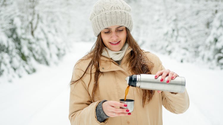 Woman In Brown Coat Pouring Coffee In A Thermos Cap