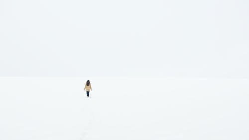 Person in Black Pants Walking on Snow Covered Ground